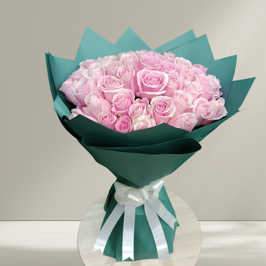 Bouquet of pink roses wrapped in green paper with a white ribbon