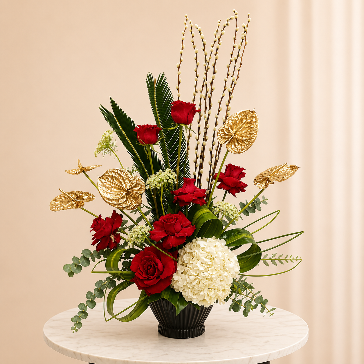 A decorative floral arrangement in a black ribbed vase, featuring red roses, a large white hydrangea, green foliage, and metallic gold accents, online flowers delivery UAE, flower online.
