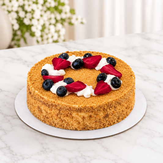 A round cake with a d with a ring of white whipped cream and fresh berries including blueberries and sliced red strawberries, for birthdays delivery across UAE.