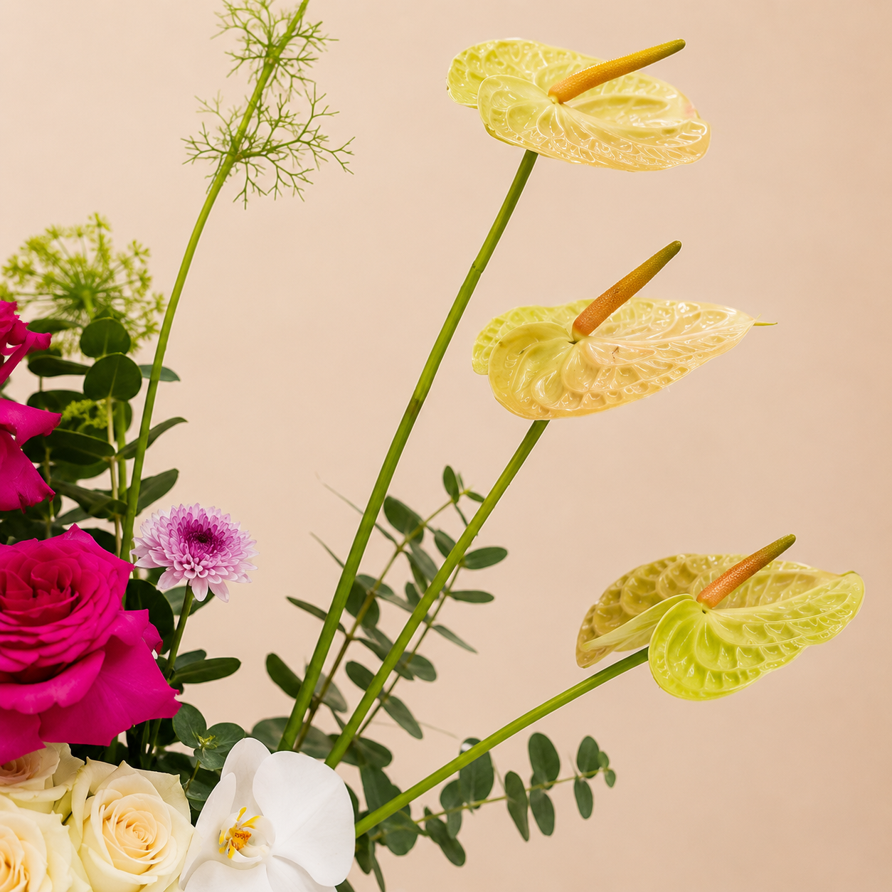 A close-up floral arrangement featuring pale yellow anthuriums with green stems, bright pink and white roses, a white orchid, and green foliage online flowers delivery Dubai
