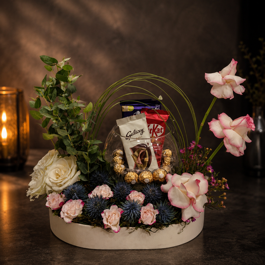 Luxury floral arrangement with premium chocolates in a glass bowl, fresh roses, and seasonal flowers, delivery Dubai, online flowers.