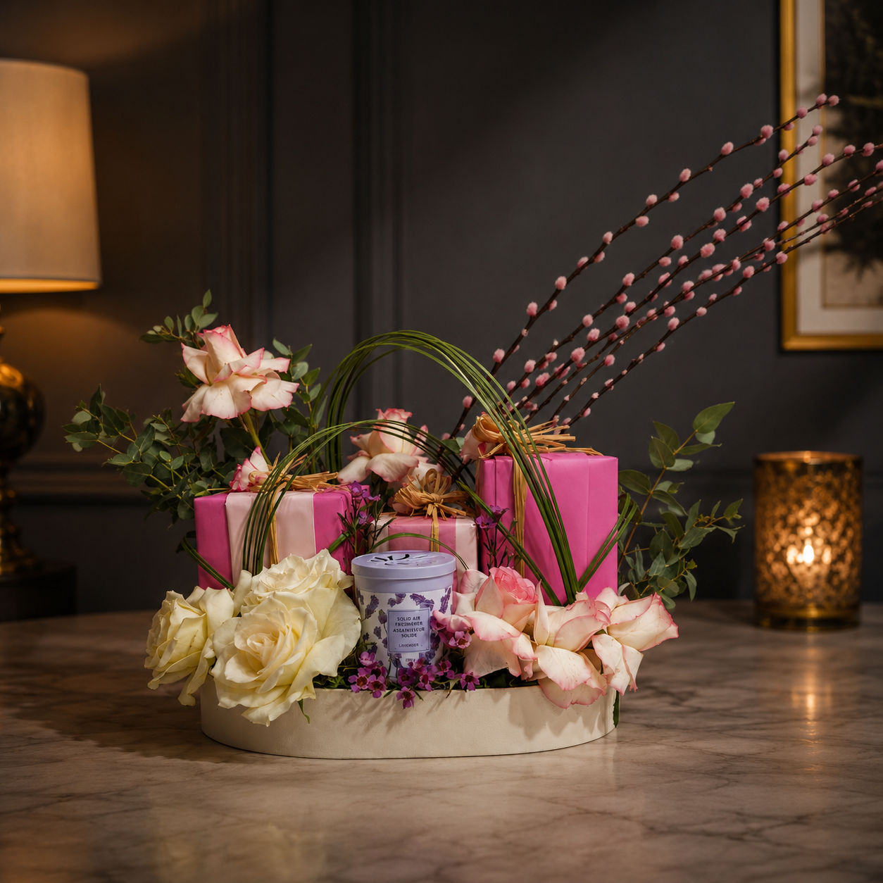 Decorative floral arrangement with pink and white flowers on a oval tray, featuring a purple candle and gift box.