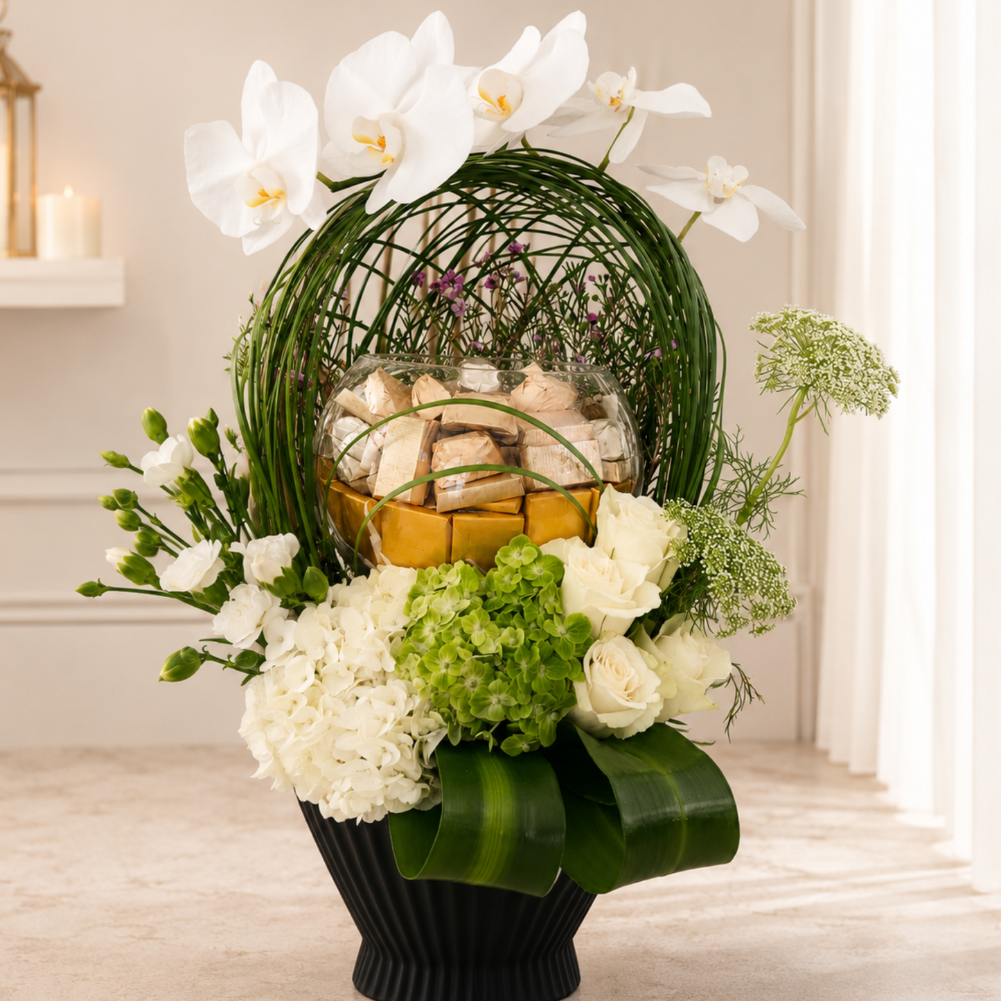 Luxury white Phalaenopsis arrangement with chocolates in a black designer vase. online flowers arrangement delivery Dubai.