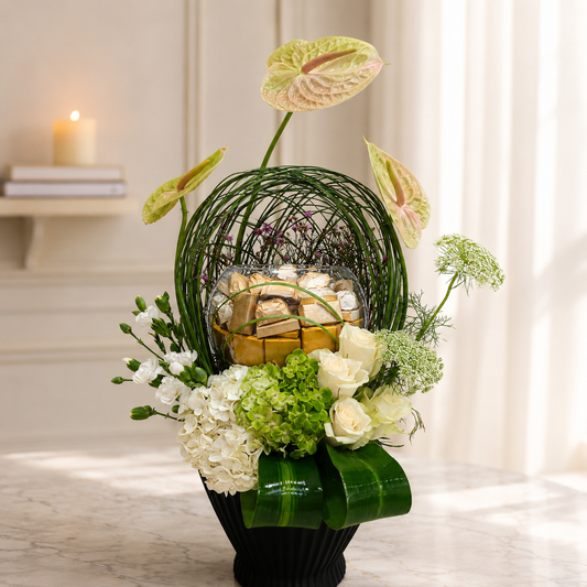 Luxury cream Anthurium floral arrangement with premium chocolates in a black designer vase.