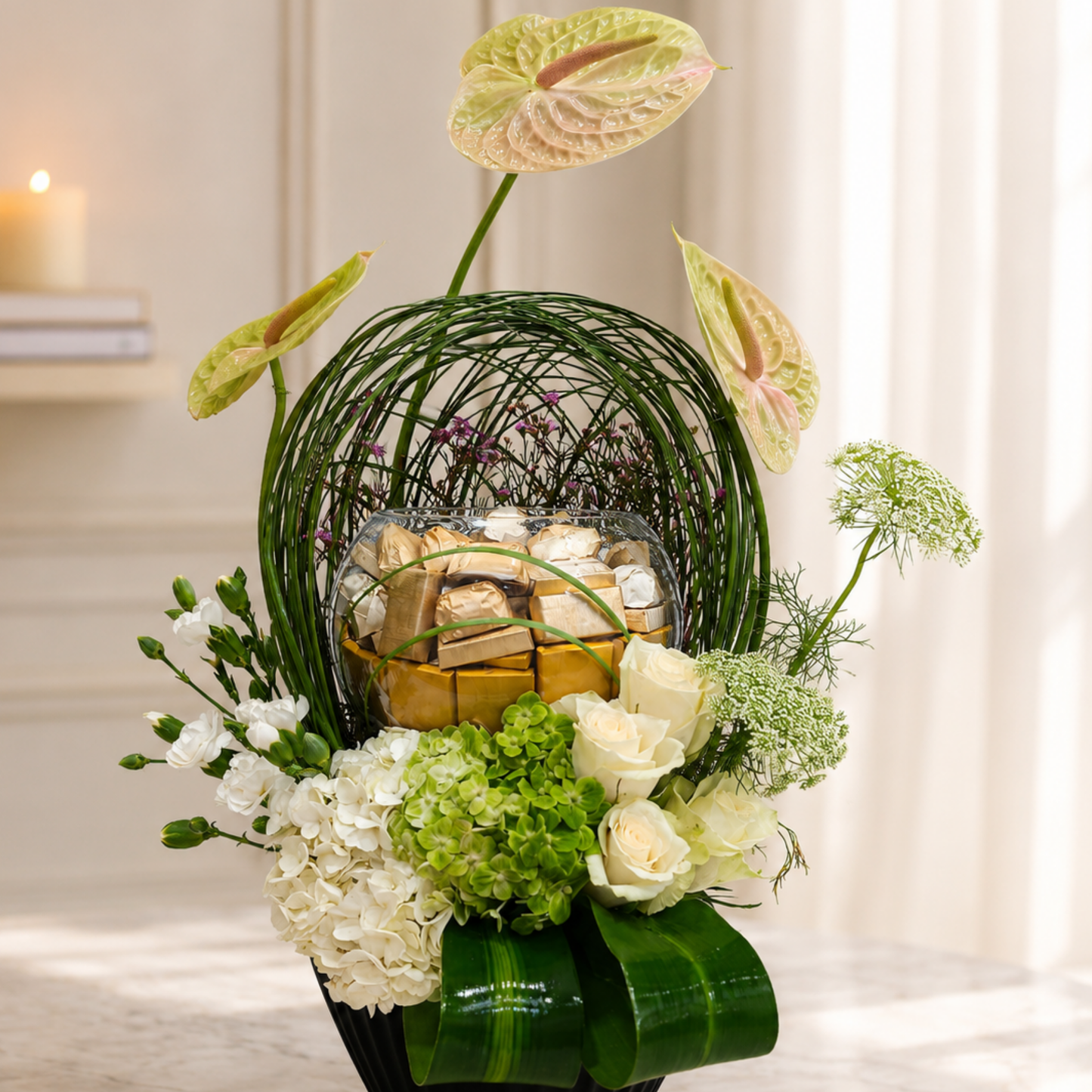 Luxury cream Anthurium floral arrangement with premium chocolates in a black designer vase. online flowers arrangement delivery Dubai.